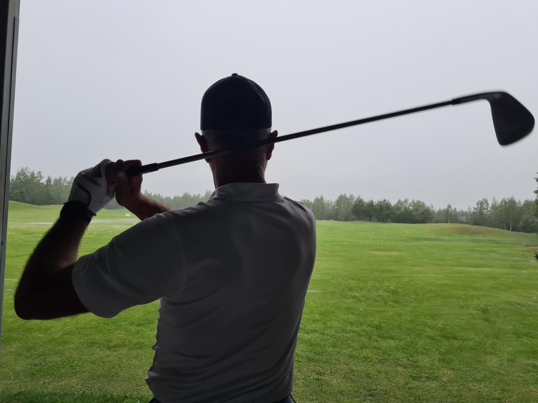 Golfer swinging club on green course